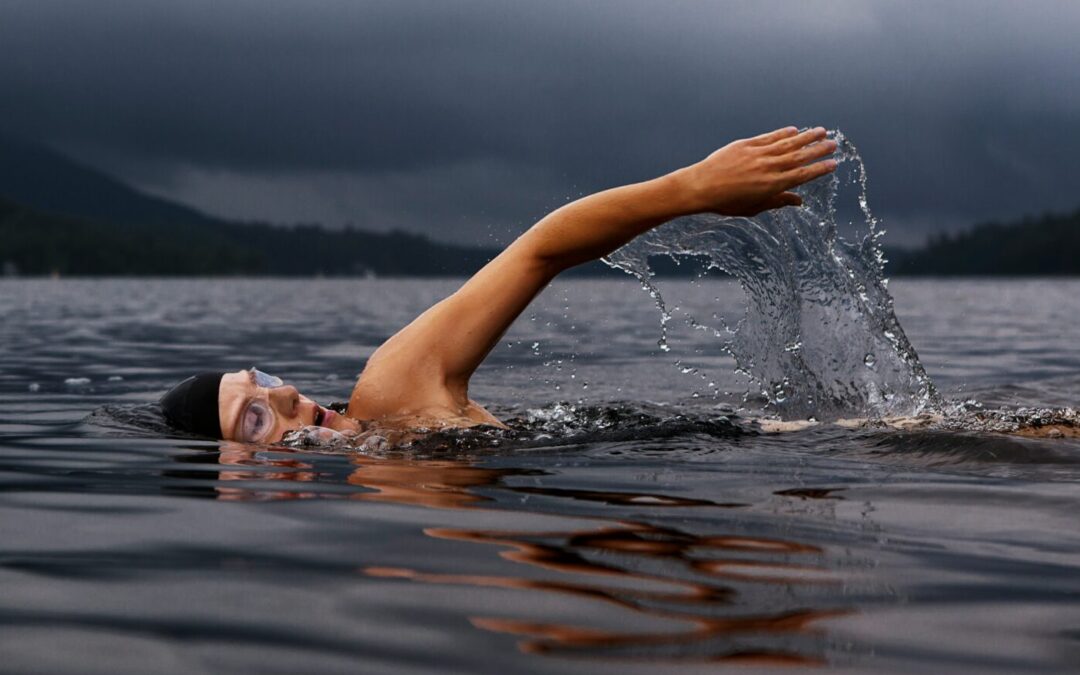 Frau mit Schwimmkappe und -brille schwimmt im See
